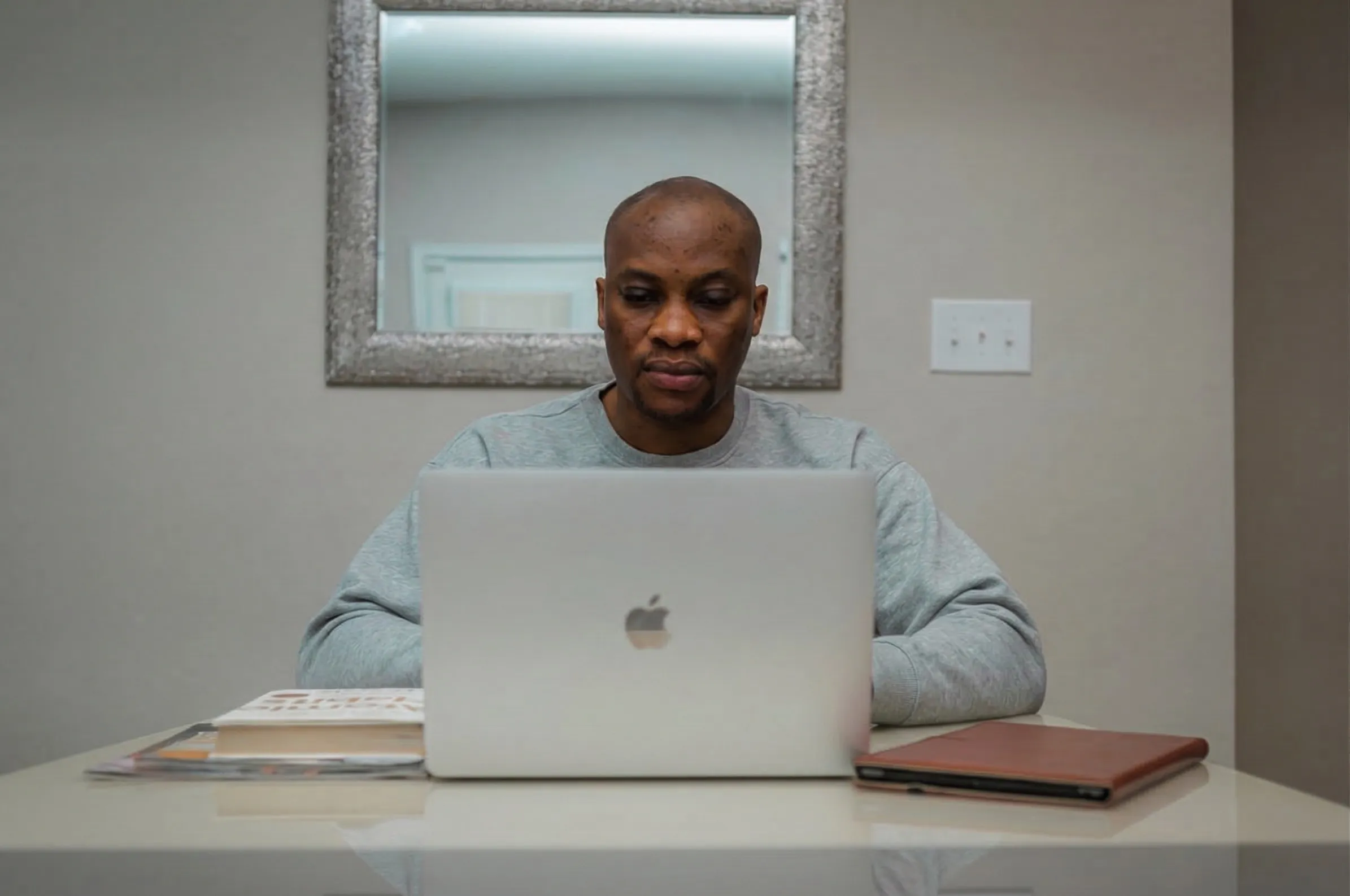 A man focused on his laptop at a desk at home